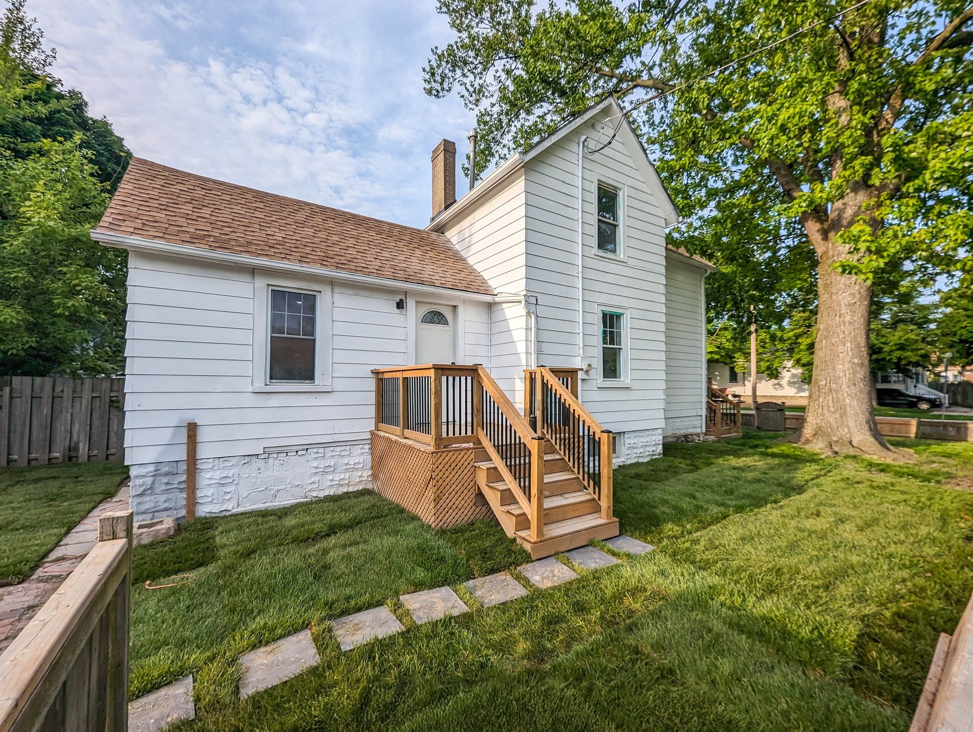 White cottage exterior with clean blue sky after sky replacement