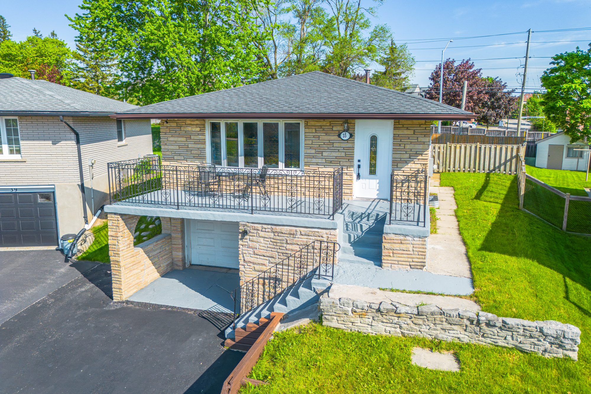 Stone-front bungalow exterior with a raised deck and bright blue sky