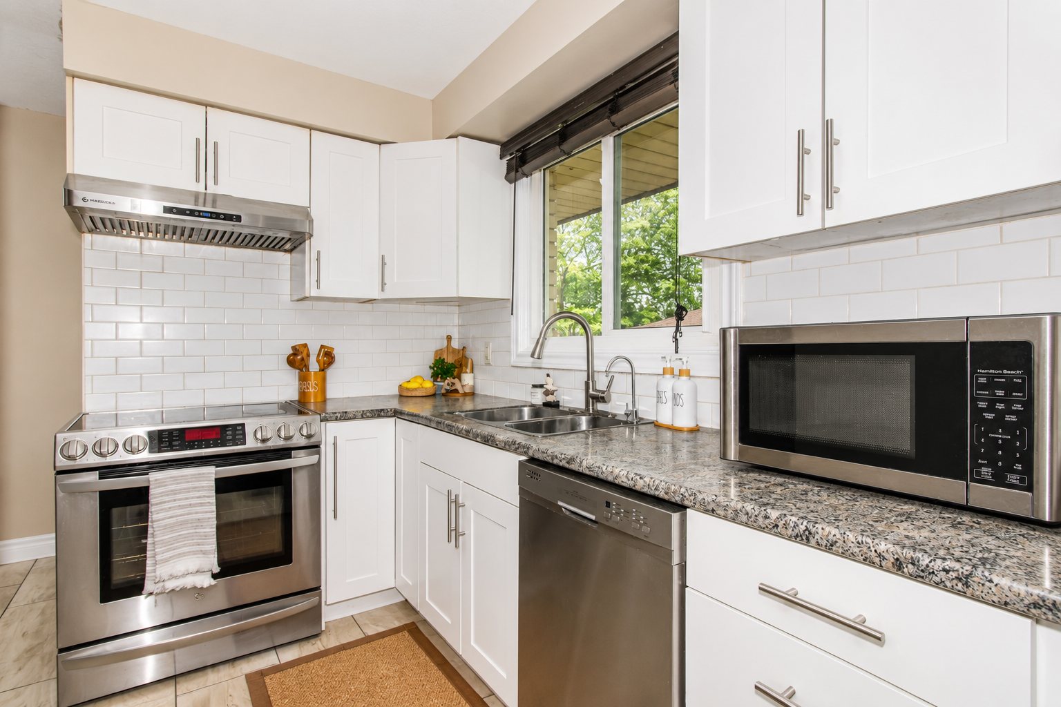 Bright white kitchen with stainless steel appliances and granite countertops